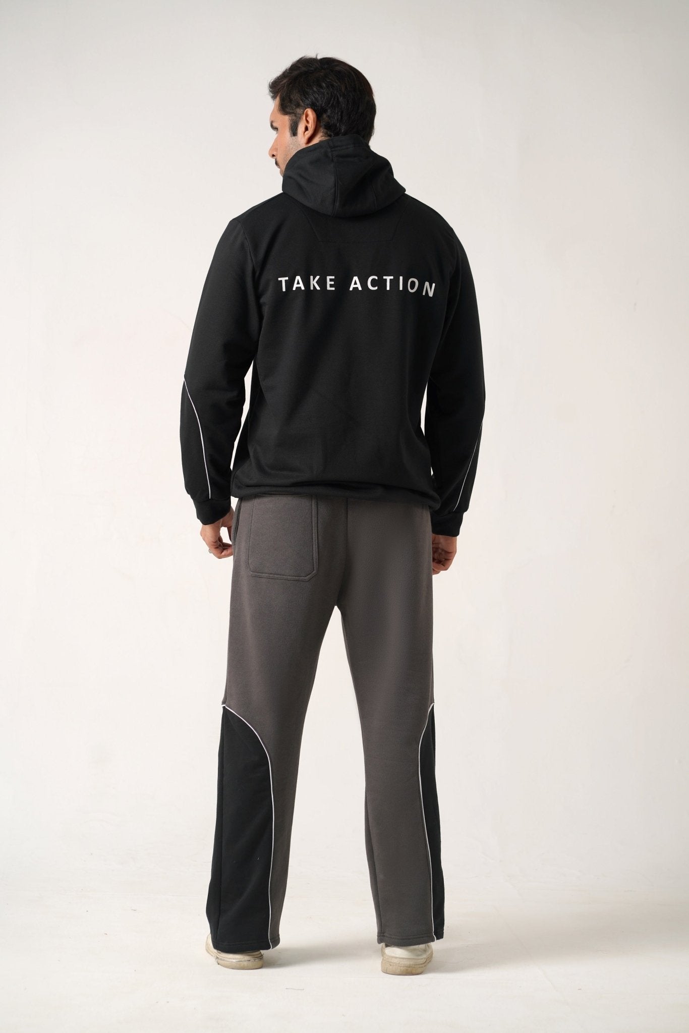 Person wearing a black hoodie with 'TAKE ACTION' text on the back, standing against a white background.