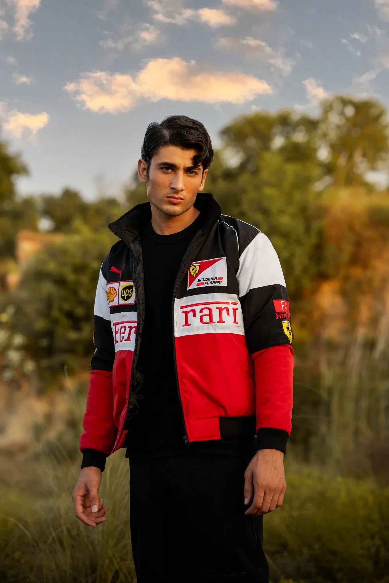 A man wearing a Ferrari Jacket with a red and black color scheme, featuring embroidered Ferrari and F1 logos.