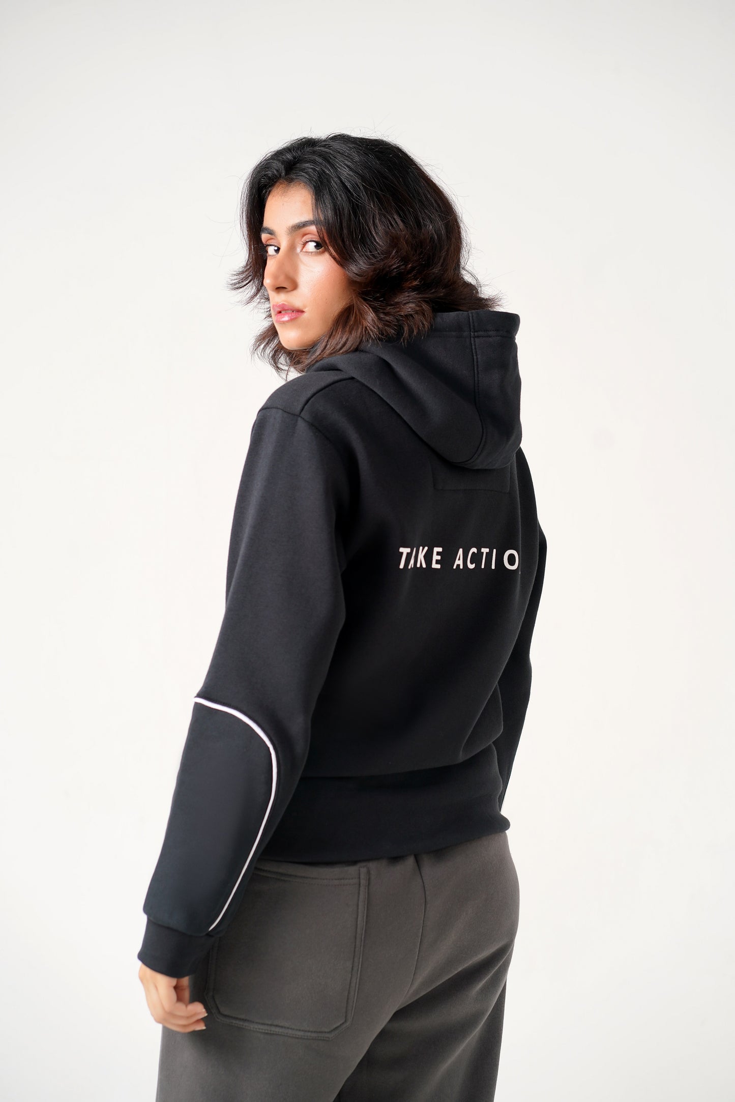 Person wearing a black hoodie with 'TIKE ACTIO' text on the back against a white background