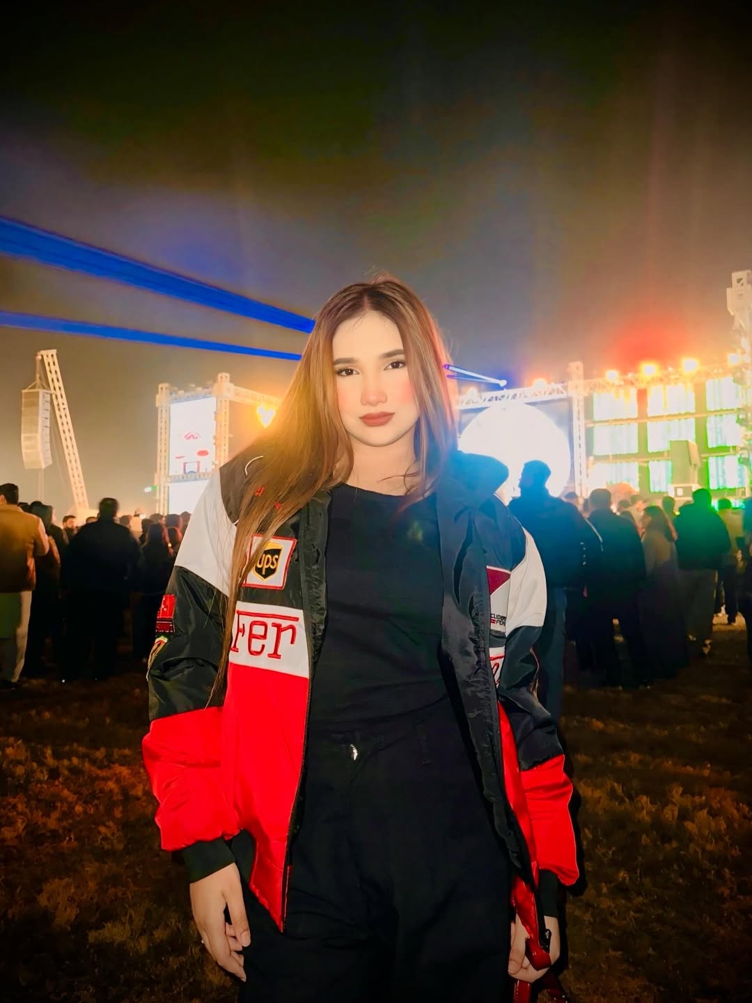 Woman wearing a red ferrari f1 jacket with a blurred event background
