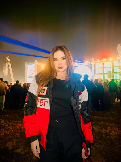 Woman wearing a red ferrari f1 jacket with a blurred event background