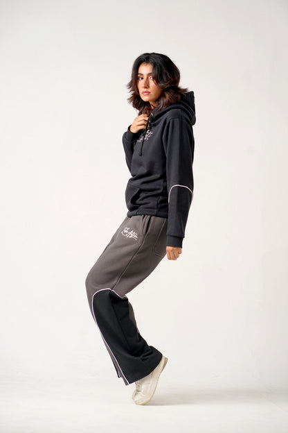 Person wearing a black hoodie and gray pants on a white background