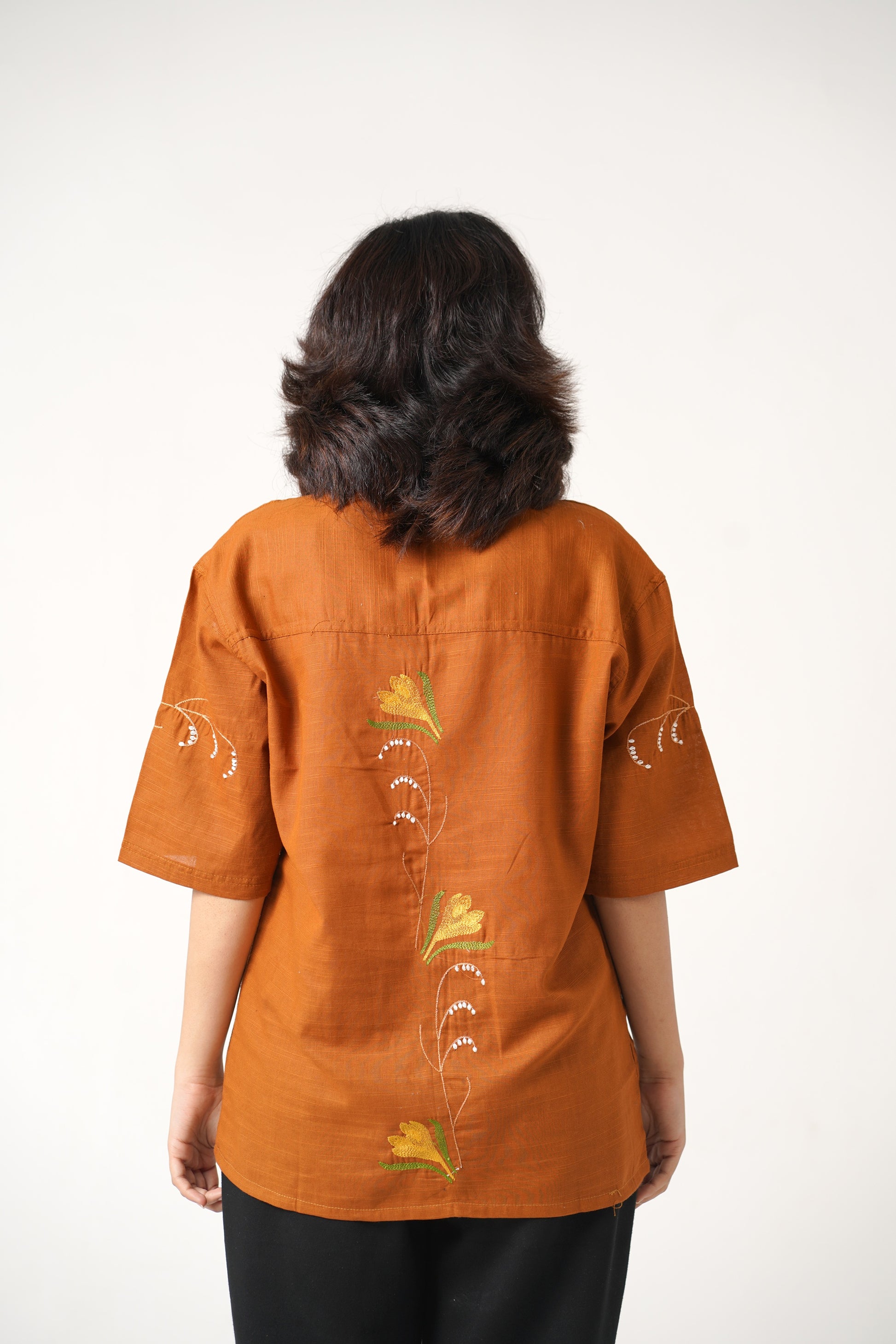 Person wearing an orange shirt with floral patterns on a white background