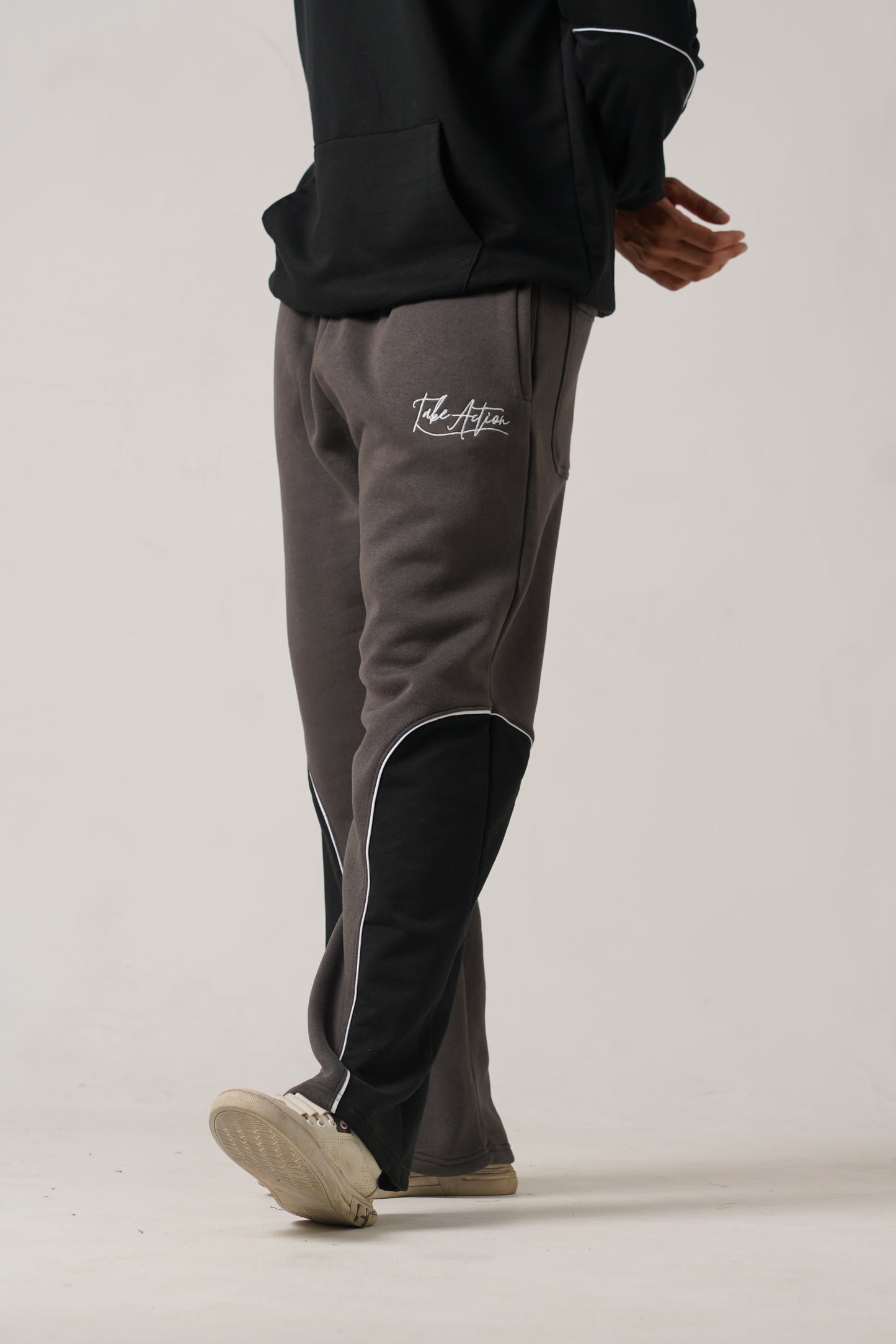 Person wearing dark gray tracksuit with visible branding on a light background