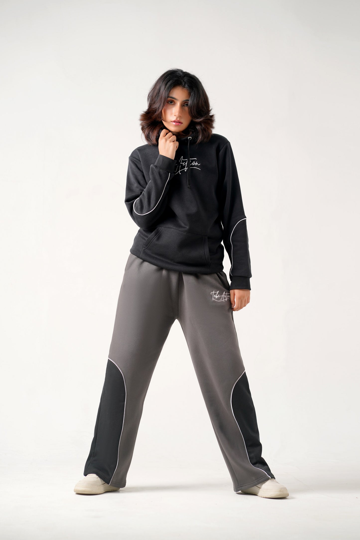 Person wearing a black hoodie and gray pants on a white background