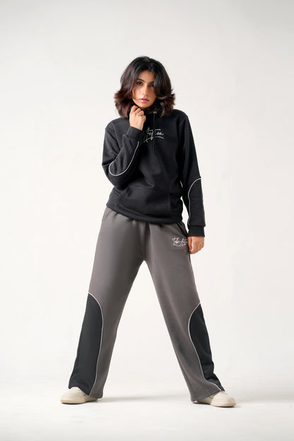 Person wearing a black hoodie and gray pants on a white background