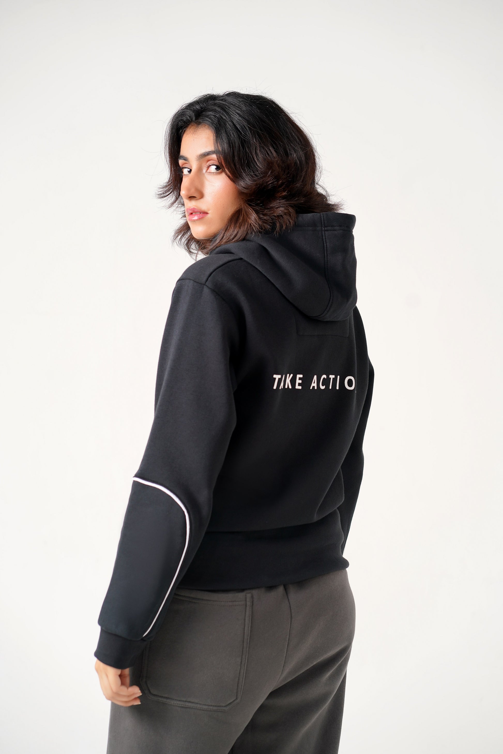 Person wearing a black hoodie with 'TIKE ACTIO' text on the back against a white background
