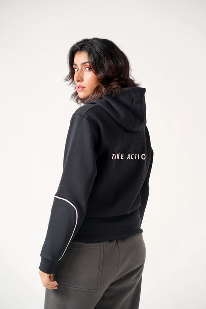 Person wearing a black hoodie with 'TIKE ACTIO' text on the back against a white background