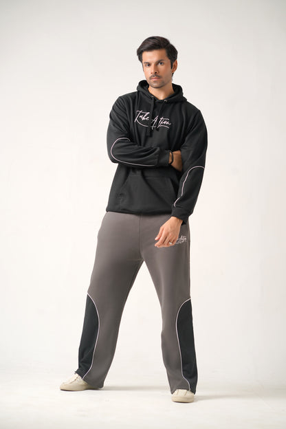Man wearing a black hoodie and gray pants with branding on a white background