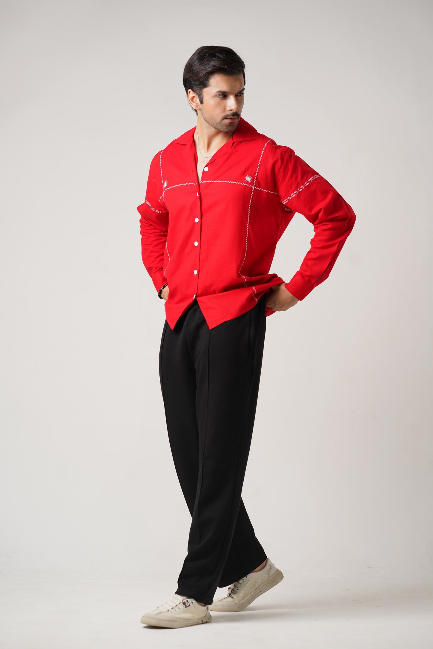 Man wearing a red shirt and black pants on a white background