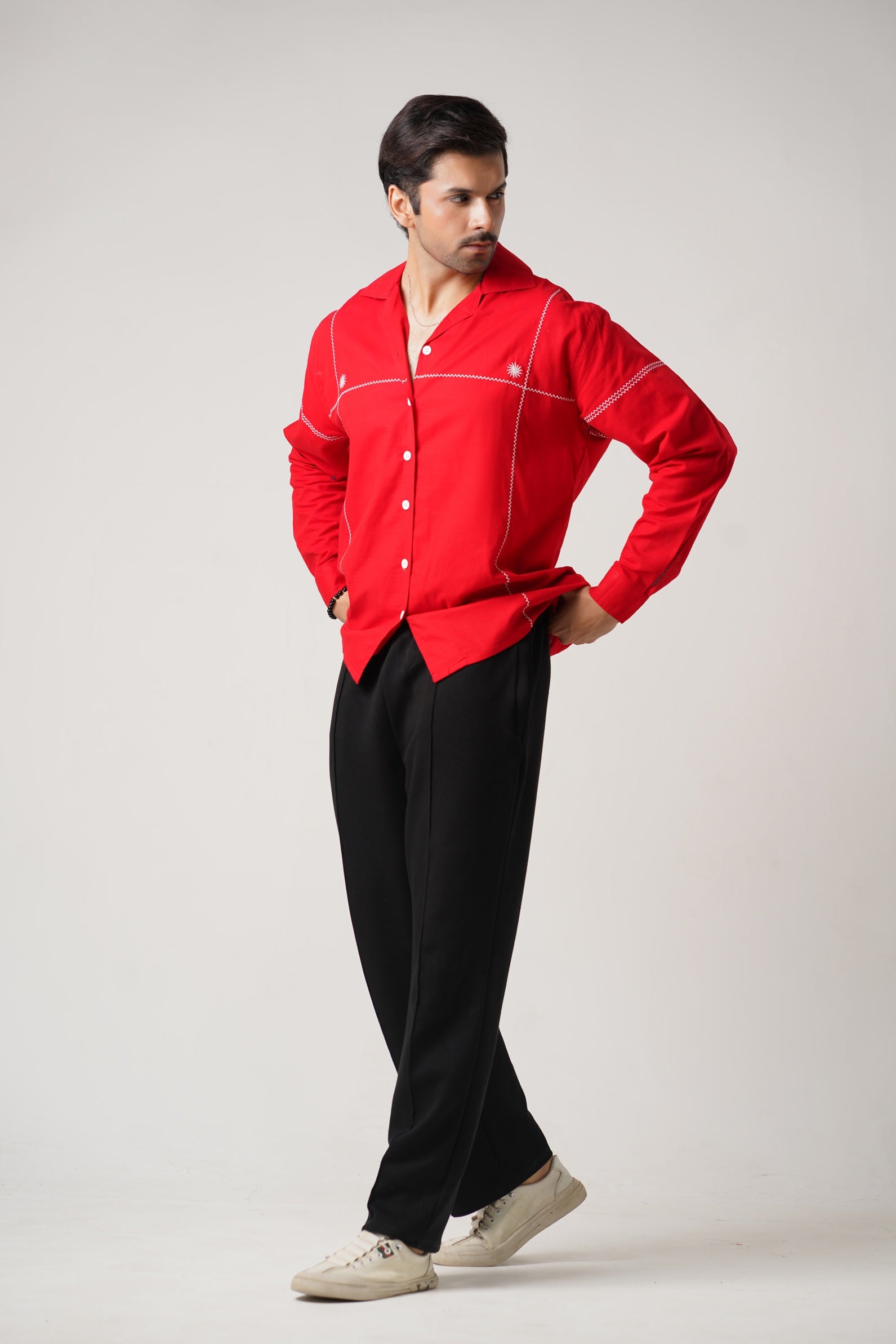 Man wearing a red shirt and black pants on a white background