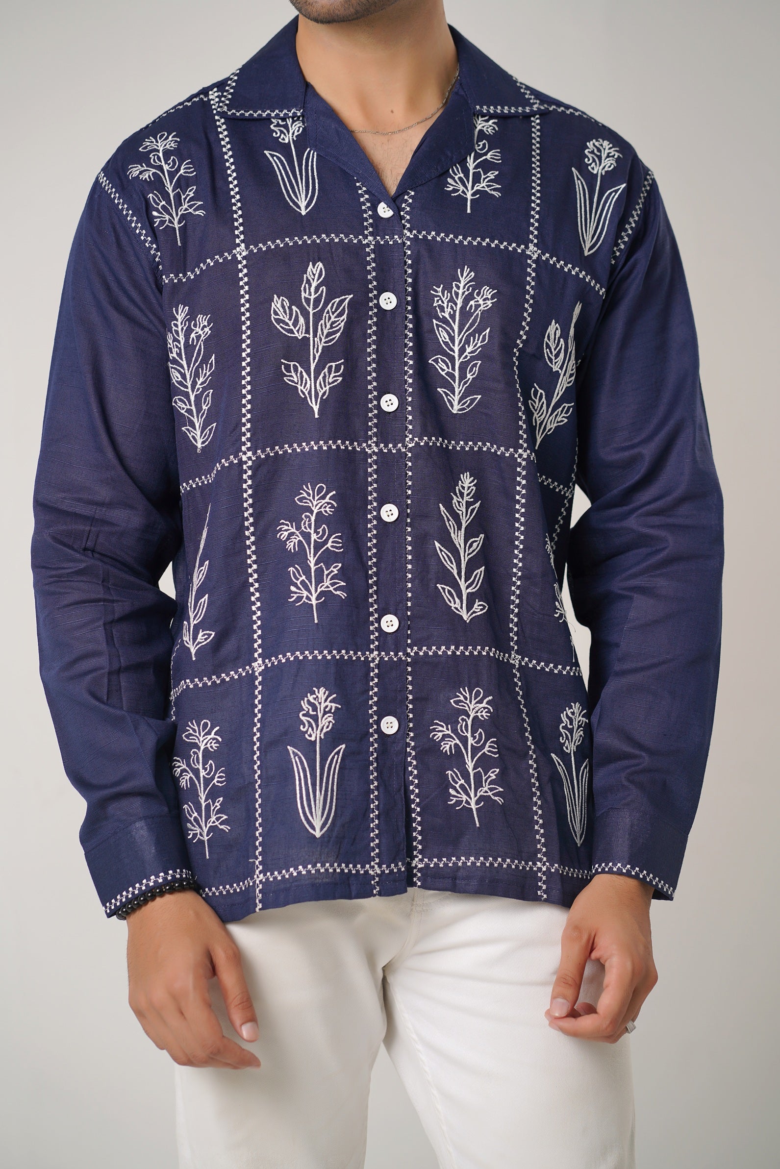 Navy blue shirt with white floral patterns worn by a person on a plain background