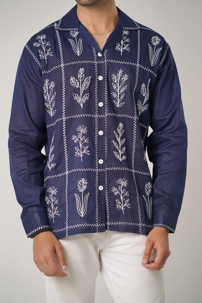 Navy blue shirt with white floral patterns worn by a person on a plain background