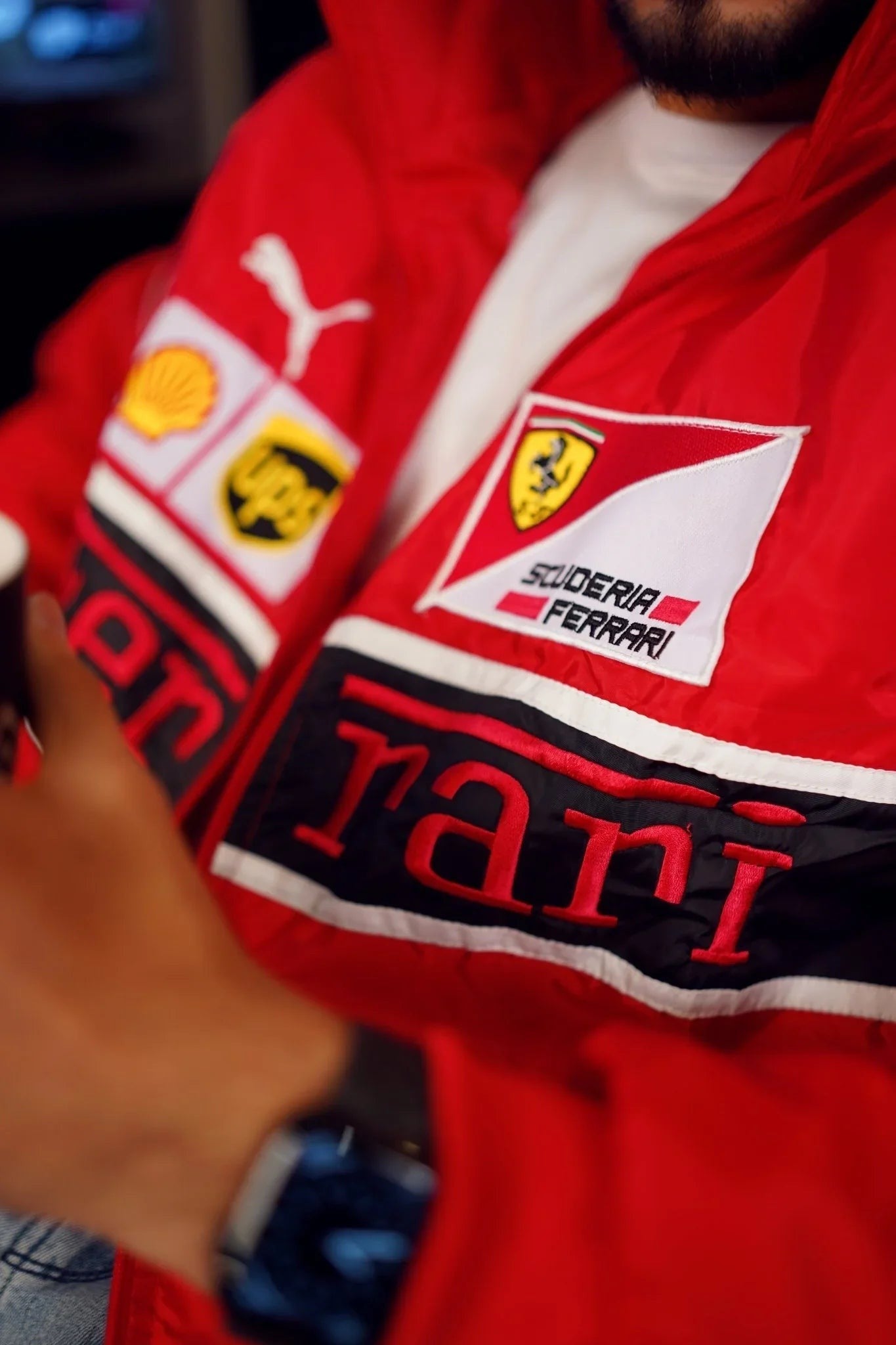 Koti Apparels red F1 bomber jacket with embroidered Scuderia Ferrari logo and text, Puma and sponsor patches on sleeve.