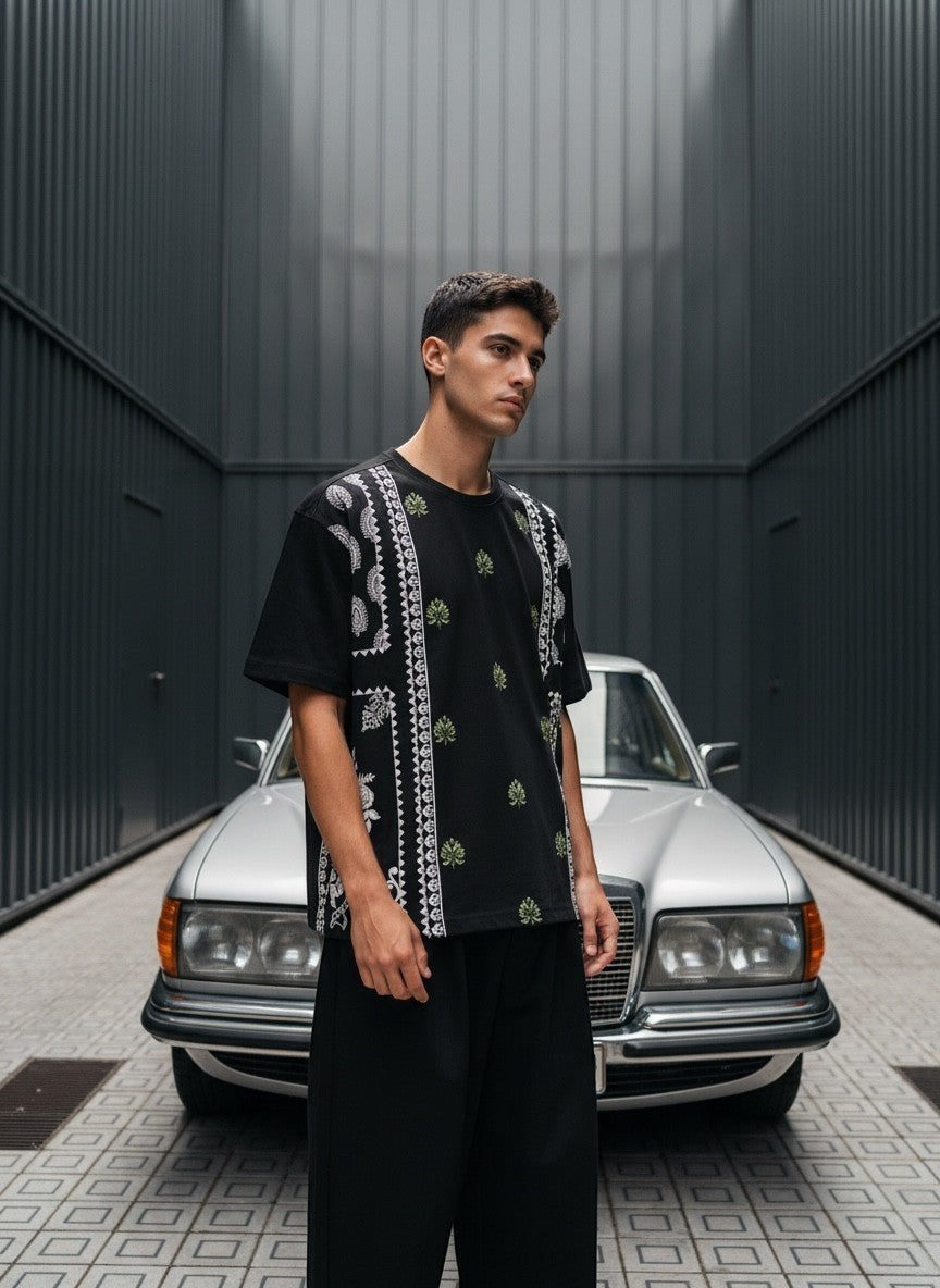 Koti Apparels black cotton blend t-shirt with graphic print featuring paisley and botanical motifs in green and white.