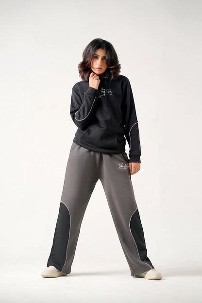 Koti Apparels black heavyweight cotton fleece hoodie with embroidered logo and grey trousers with black panels and embroidered logo.