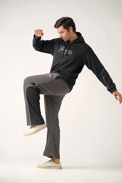 Koti Apparels black heavyweight cotton fleece hoodie with embroidered "TAKE ACTION" and matching charcoal grey trousers with side stripe detail.