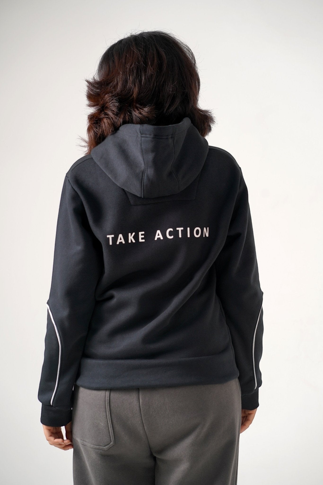 Koti Apparels black heavyweight cotton hoodie with "TAKE ACTION" text on back and white piping on sleeves.