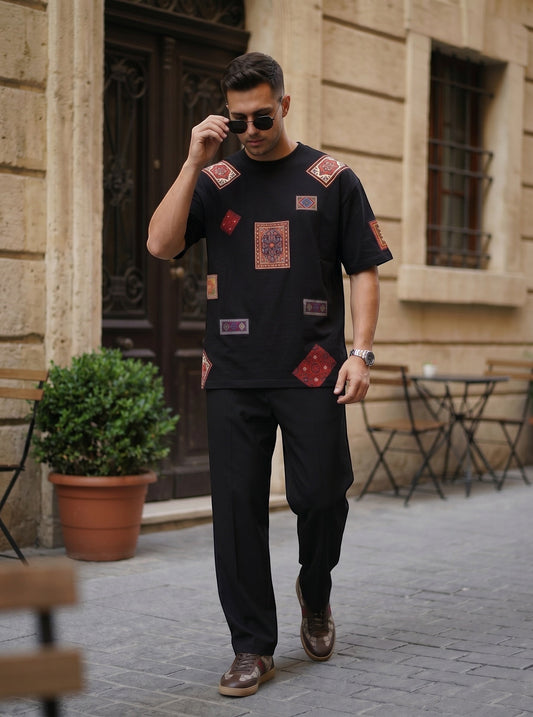Koti Apparels black cotton t-shirt with vintage rug-inspired patchwork, worn by a man in a relaxed street setting.