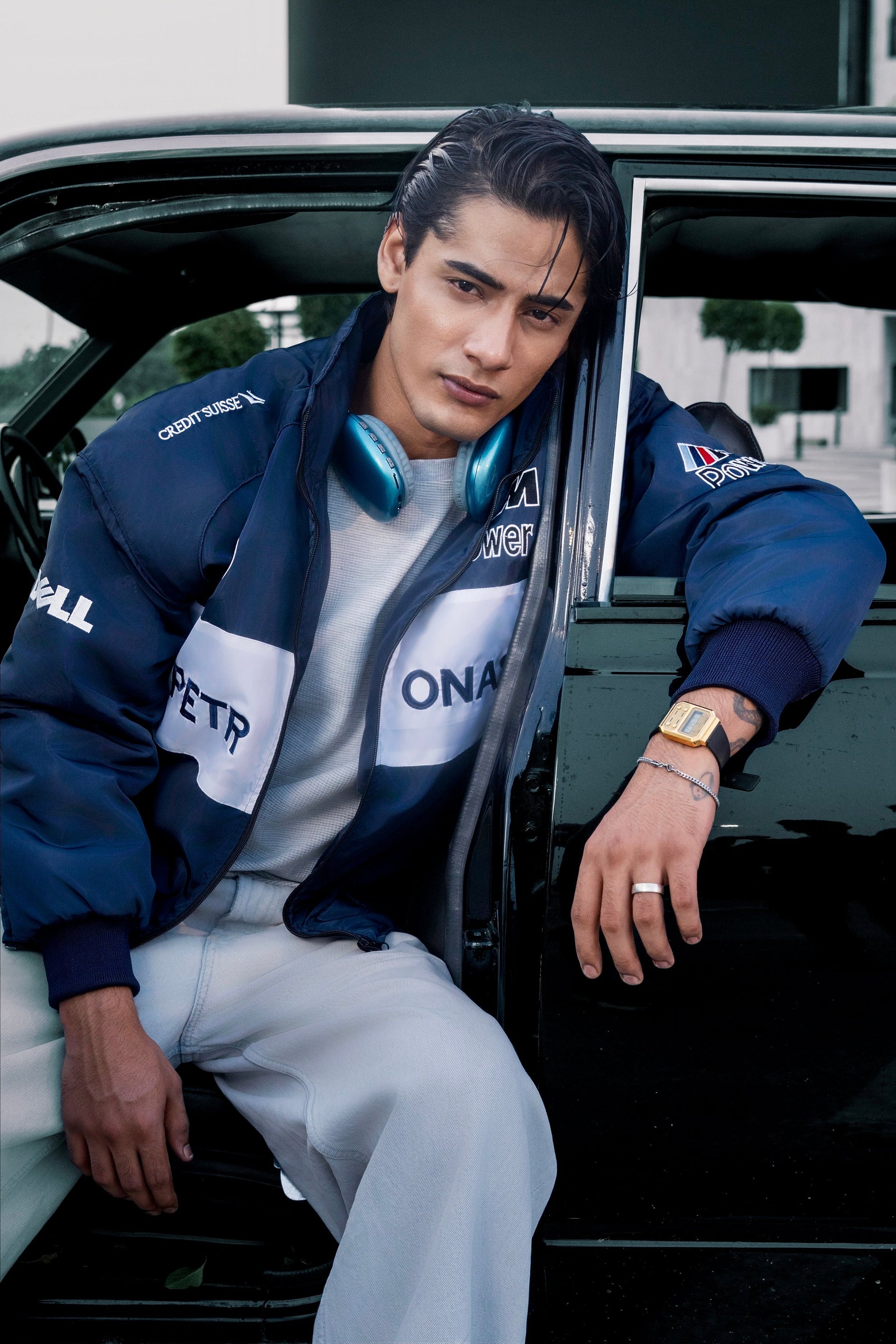 Koti Apparels BMW racing jacket in navy blue with white embroidered logos worn by a man leaning against a black car