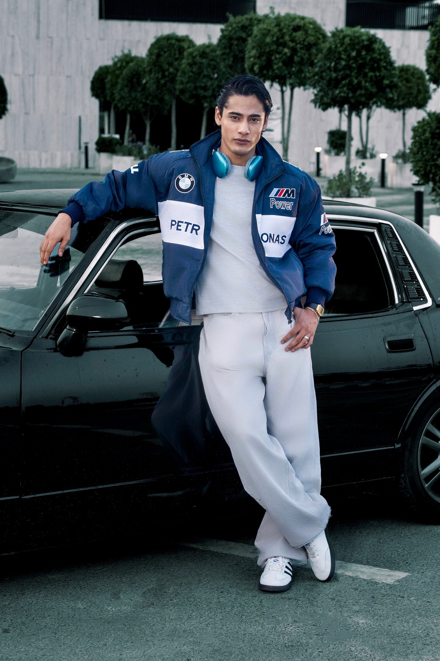 Koti Apparels BMW racing jacket with embroidered logos worn by a man leaning against a black car