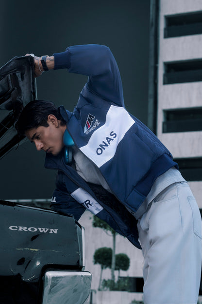 Koti Apparels BMW racing jacket in navy and white with embroidered logos worn by a man checking a car engine