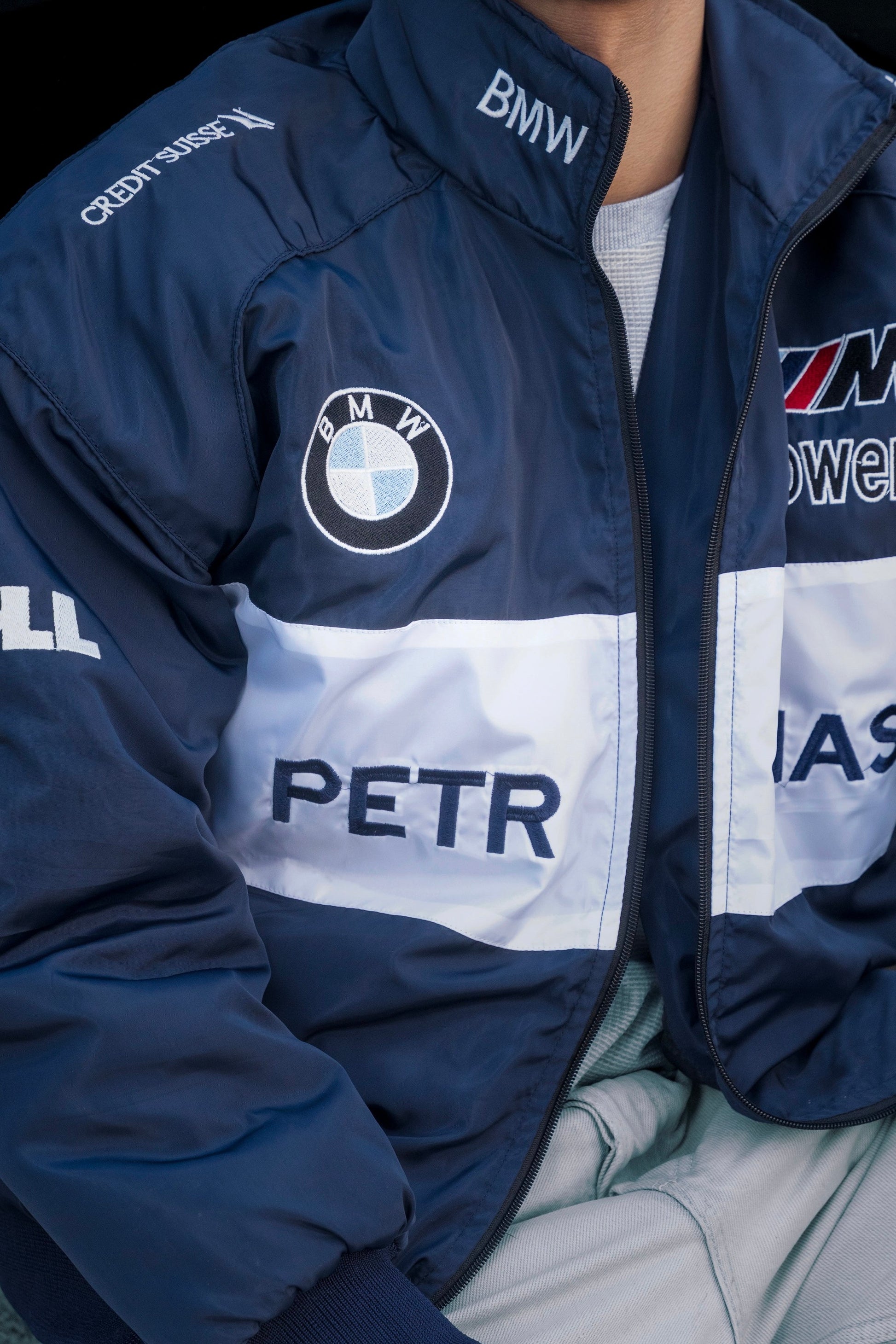 Koti Apparels navy blue BMW racing jacket featuring embroidered motorsport logos and a bold white chest stripe.