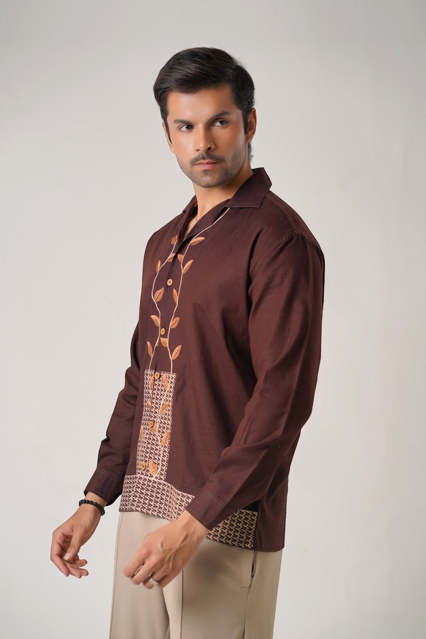 Koti Apparels unisex brown khaddar shirt with leaf embroidery on the placket and geometric pattern on the hem. Open collar, button-down front, and structured cuffs.