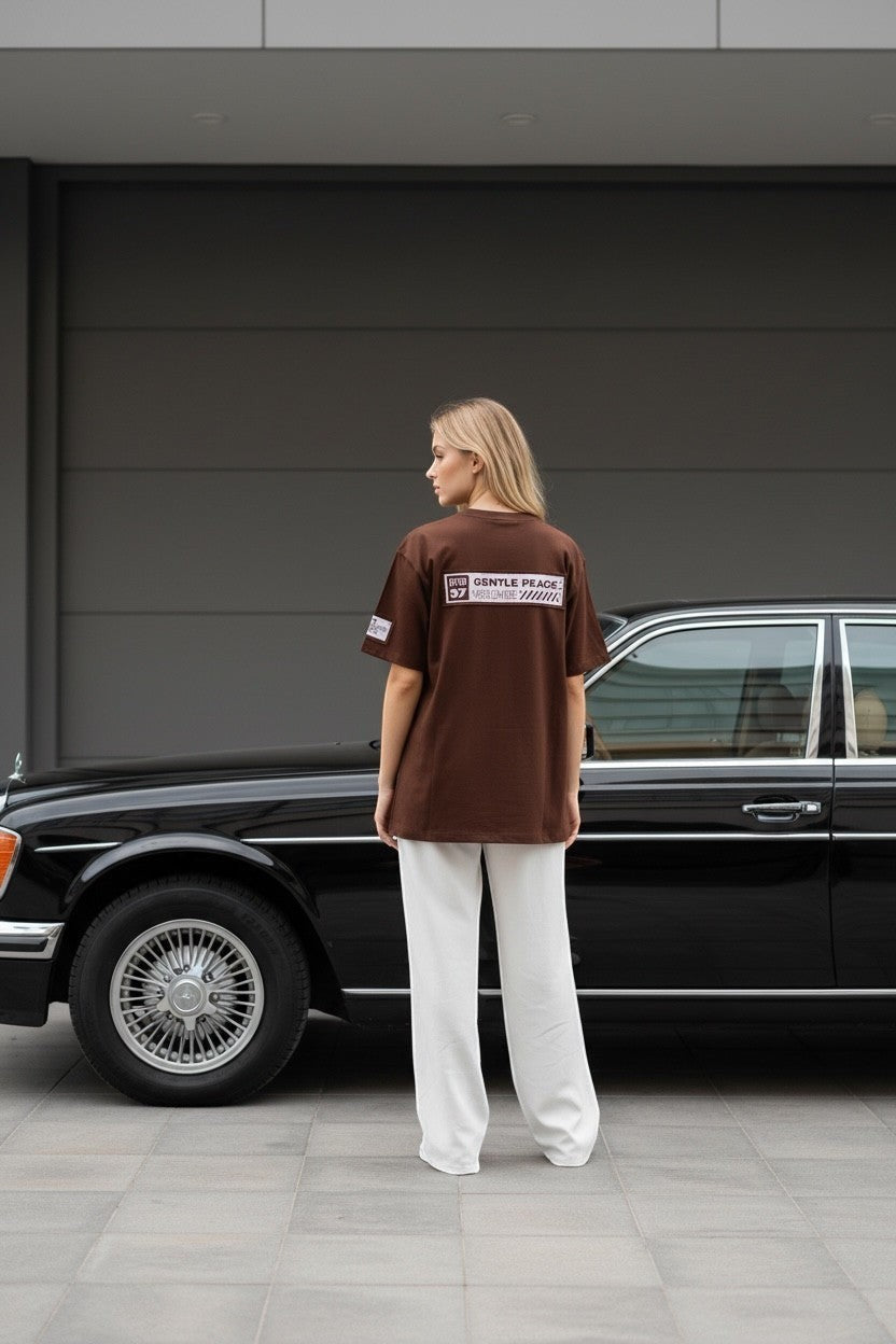 Koti Apparels brown cotton t-shirt with graphic print and bold numbering, relaxed fit, worn by a woman standing next to a vintage car.