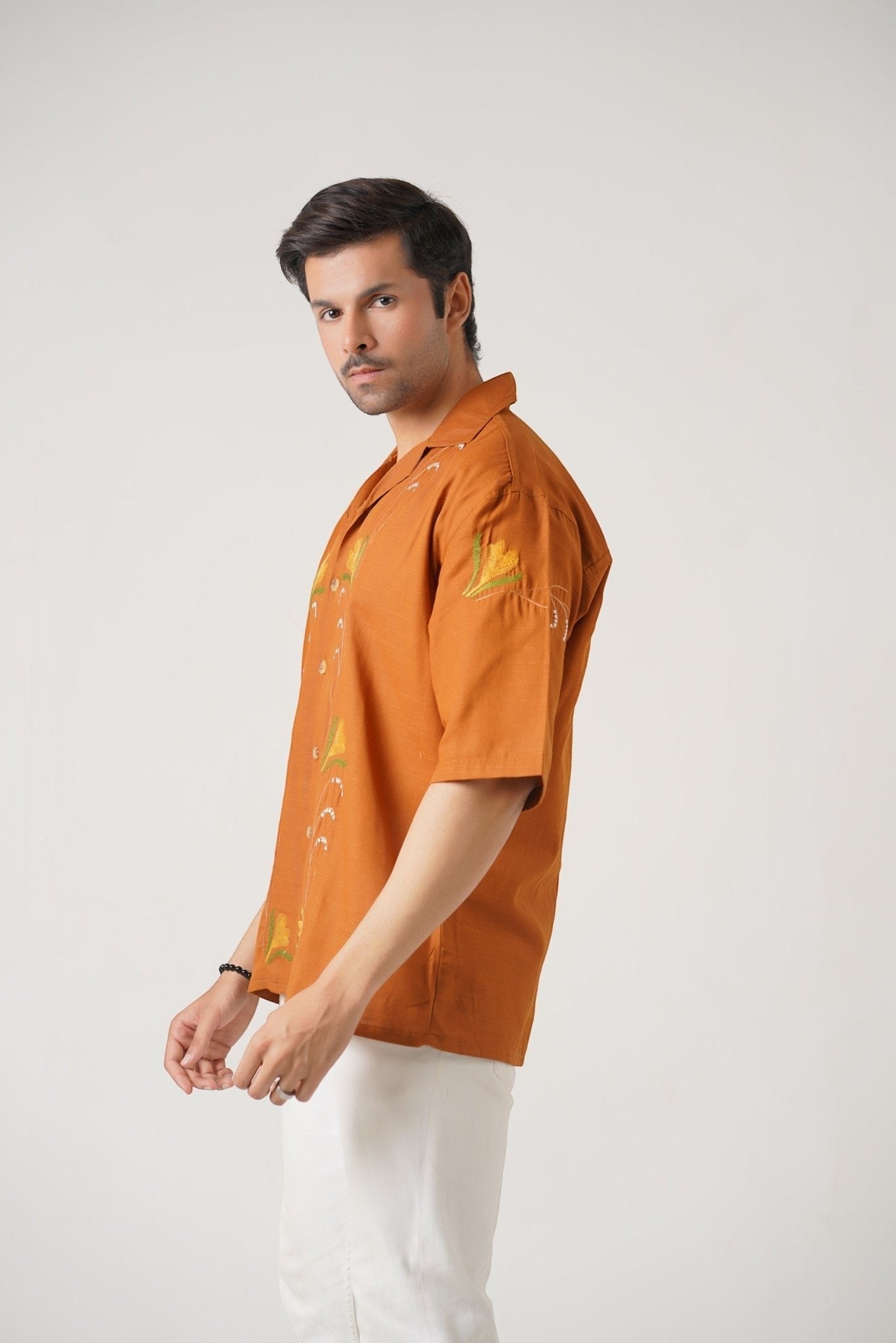Koti Apparels burnt orange embroidered unisex shirt with floral motifs and wooden buttons. Relaxed fit, half sleeves.