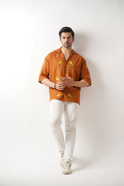 Koti Apparels burnt orange unisex shirt with embroidered floral motifs and wooden buttons. Relaxed fit, half sleeves.