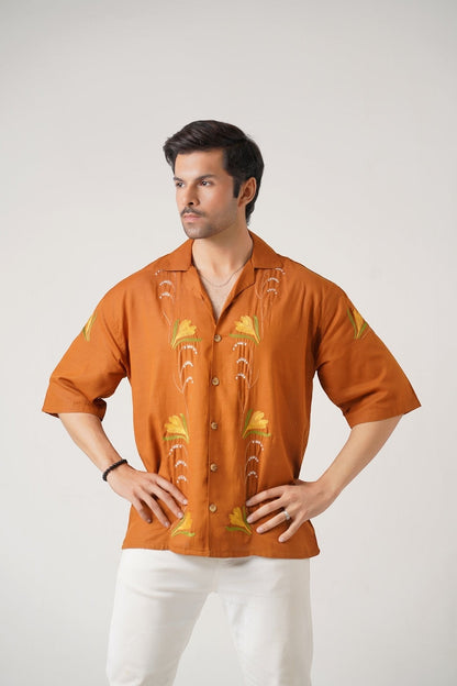 Koti Apparels burnt orange unisex shirt with floral embroidery, wooden buttons, and spread collar.