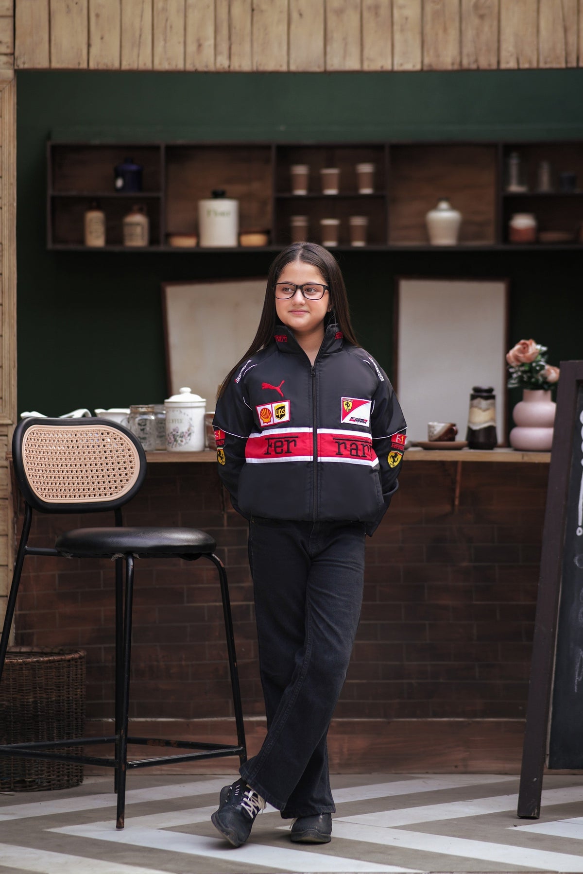 Koti Apparels black Scuderia Ferrari racing jacket with red and white details worn by a girl in a cafe setting