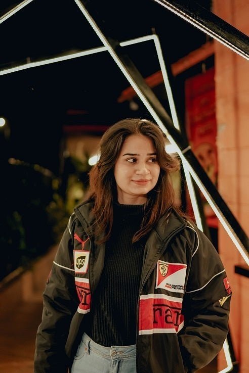 Koti Apparels black vintage Y2K Formula 1 racing jacket with embroidered logos and red racing stripes, worn by a woman.