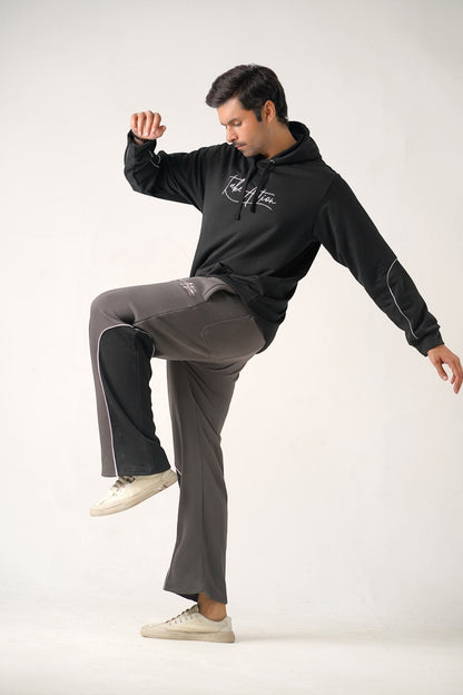 Koti Apparels heavyweight unisex winter fleece trousers in charcoal grey with black side panels and white piping. Embroidered "TAKE ACTION" logo on front.