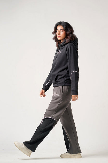 Koti Apparels black heavyweight cotton fleece hoodie with embroidered logo and grey/black panelled trousers with embroidered logo.