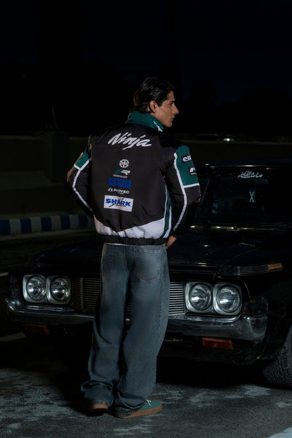 Koti Apparels Kawasaki racing jacket in black and green with Ninja branding, worn by a man leaning on a vintage car.