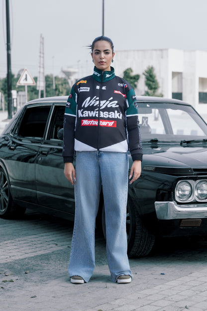 Model wearing a Koti Apparels Kawasaki racing jacket in black and green with sponsor logos, paired with blue jeans.