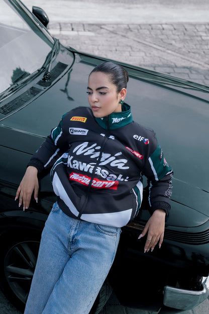 Koti Apparels Kawasaki racing jacket in black and green polyester worn by a woman leaning against a black car