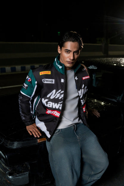 Koti Apparels Kawasaki racing jacket in black and green polyester worn by a man leaning against a car at night