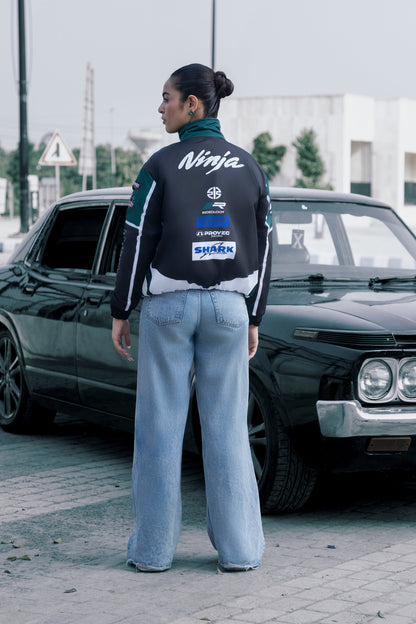 Koti Apparels Kawasaki racing jacket in black and green with sponsor logos, worn by a woman with blue jeans.