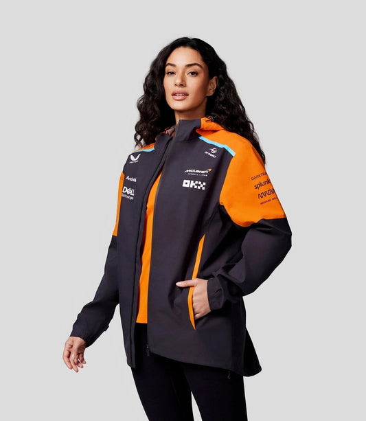 Koti Apparels McLaren Formula 1 unisex jacket in dark grey with orange accents and official team branding. Lightweight, waterproof, with zippered front and adjustable hood.