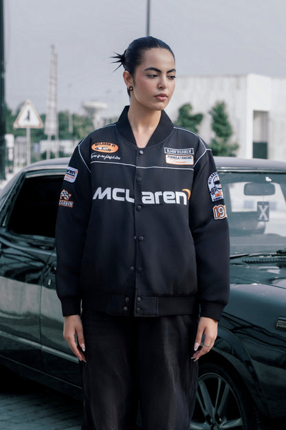 Koti Apparels black McLaren F1 racing jacket with premium needle embroidery, worn by a model outdoors.