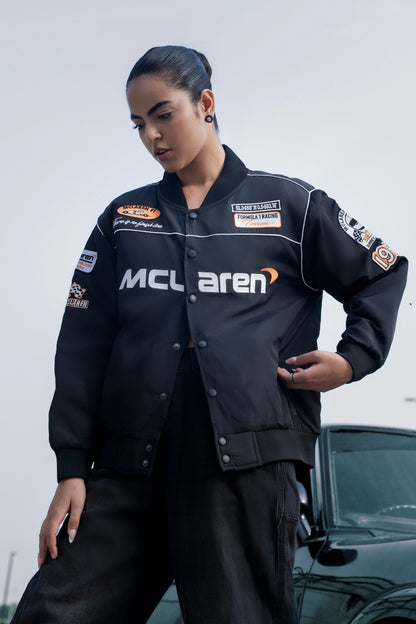 Model wearing a black Koti Apparels McLaren F1 racing jacket with premium needle-embroidered logos and zip front.