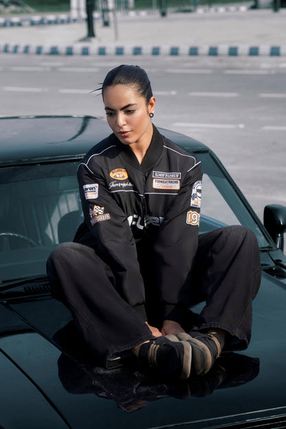 Koti Apparels McLaren F1 racing jacket in black waterproof fabric with detailed embroidery, worn by a model on a car.