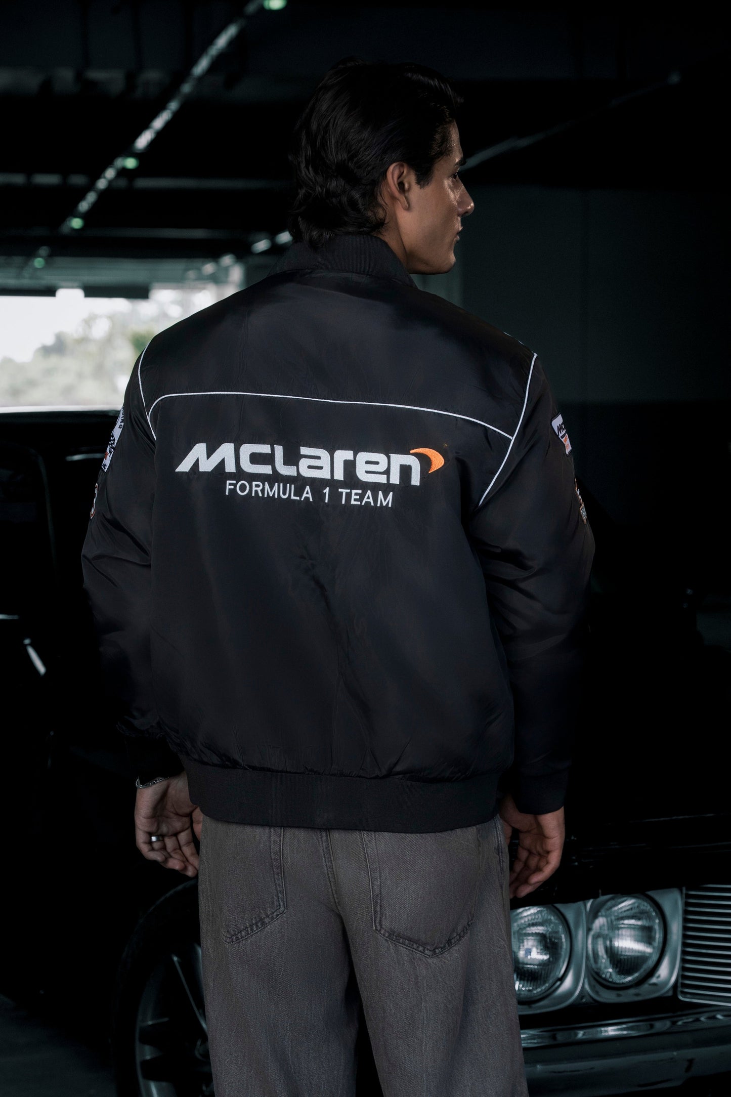 Koti Apparels black McLaren F1 racing jacket with premium needle-embroidered branding, worn by a man from the back.