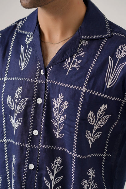 Koti Apparels navy blue cotton khaddar unisex shirt with ivory-white floral embroidery in a grid pattern and open collar.