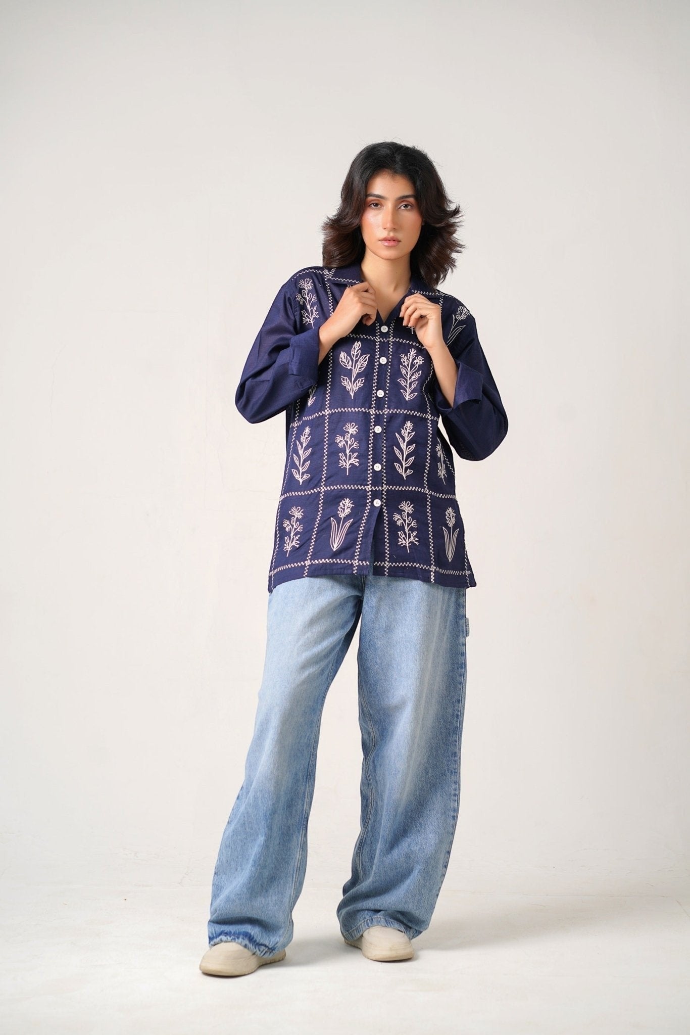 Koti Apparels navy blue cotton khaddar unisex shirt with ivory-white floral embroidery in a grid pattern, open collar, and button-down front.