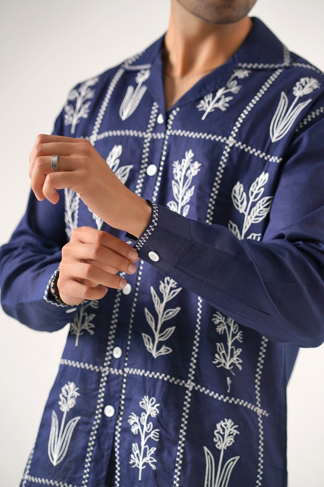 Koti Apparels navy blue cotton khaddar unisex shirt with white floral embroidery in geometric panels, open collar, and button-down front.