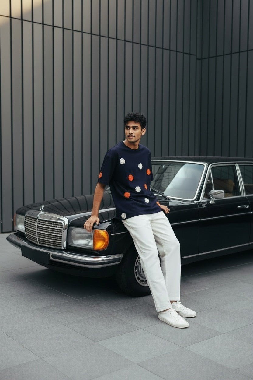Koti Apparels navy blue short sleeve t-shirt with embroidered orange and white floral appliques. Model wears white trousers.
